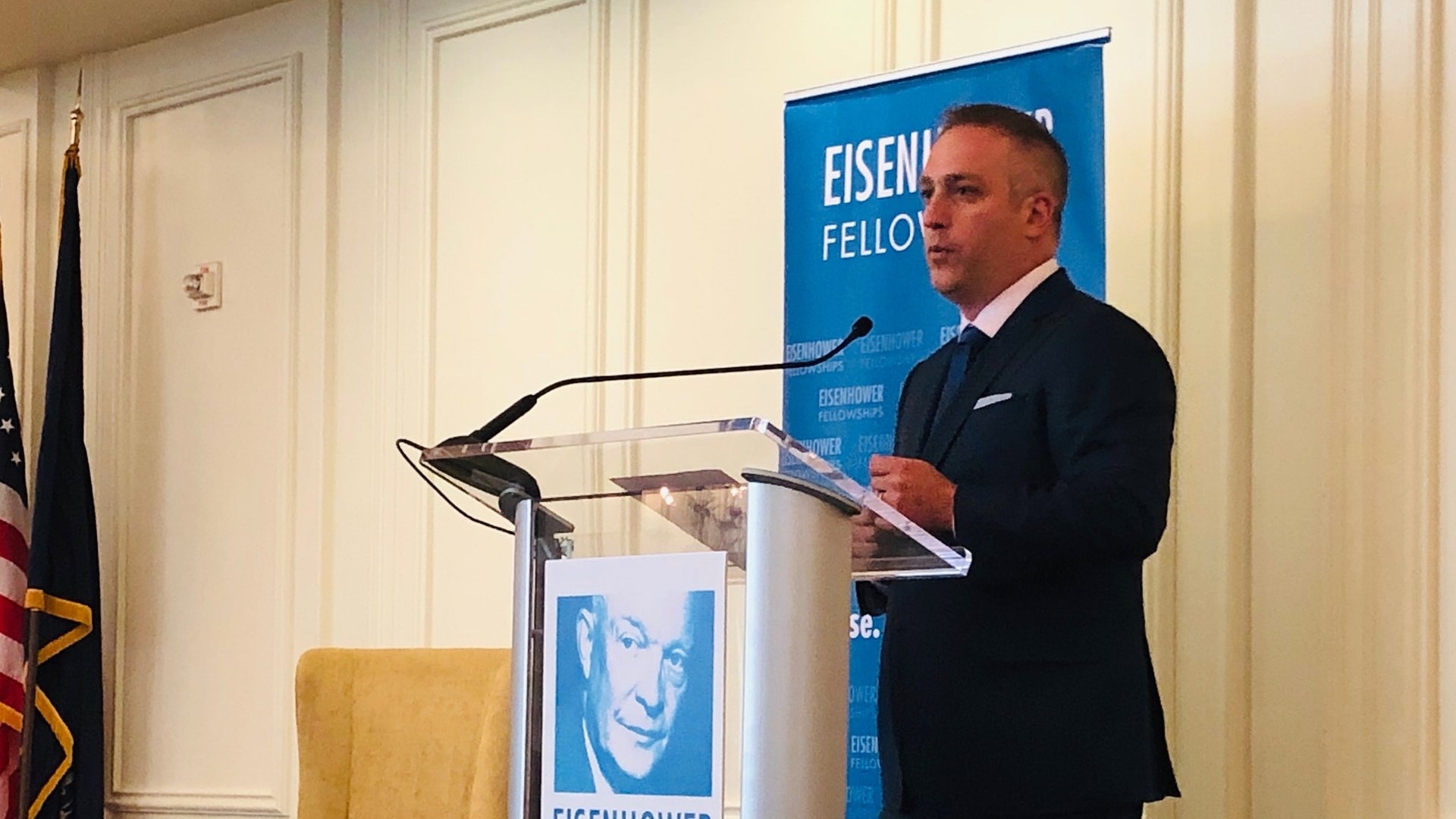 Adam Zuckerman speaking at a lectern in front of an Eisenhower Fellowships banner